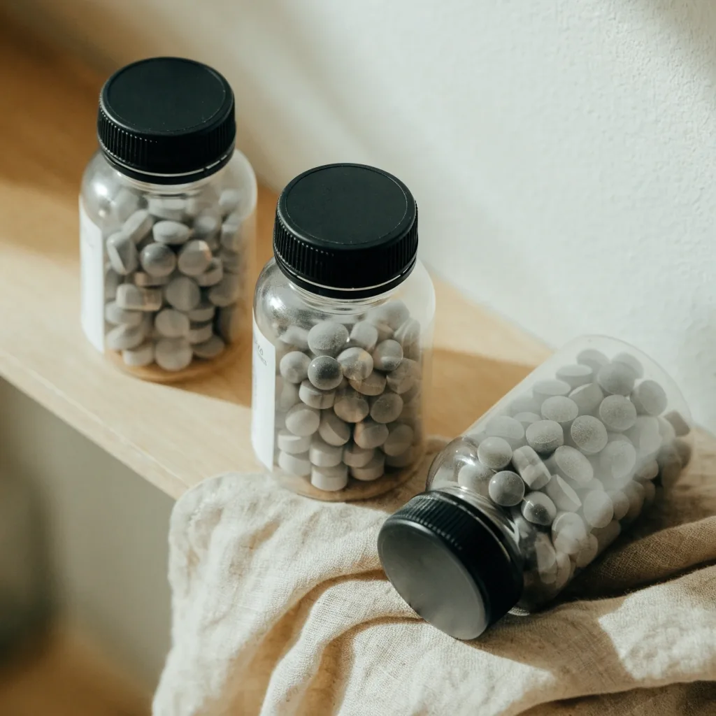 Three unlabeled clear capsule bottles arranged in a row on a bright matte surface, seen from above